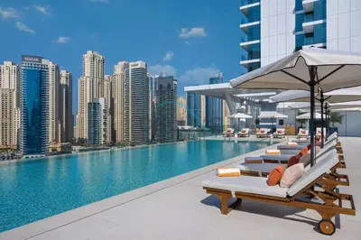 a pool with lounge chairs and an umbrella on a building at Modern 2BR in VIDA Residences Dubai Marina by Deluxe Holiday Homes in Dubai