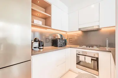 a kitchen with white cabinets and a stove top oven at Modern 2BR in VIDA Residences Dubai Marina by Deluxe Holiday Homes in Dubai