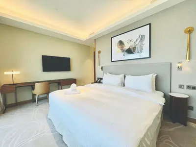 a hotel room with a large white bed and a desk at Skyline Retreat 3 Bedroom at Address Opera I Burj Khalifa & Fountain Views in Dubai