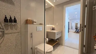 a bathroom with a toilet and a walk in shower at Private Spa 1BR Biophilic Retreat With Beach Access & Infinity Pool in Dubai