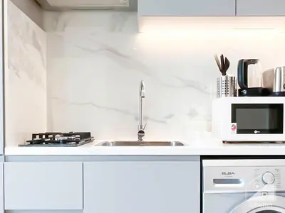 a white kitchen with a sink and a microwave at Breath taking Studio with Balcony & Stunning Views in Dubai