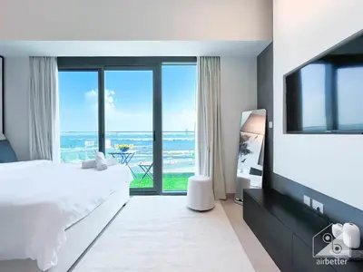 a bedroom with a large white bed and a large window at Breath taking Studio with Balcony & Stunning Views in Dubai