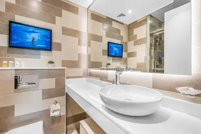 a bathroom with a sink and a tv on the wall at Beachfront 1 Bedroom Apartment on Palm Jumeirah with Stunning Sea Views and Rooftop Infinity Pool in Dubai