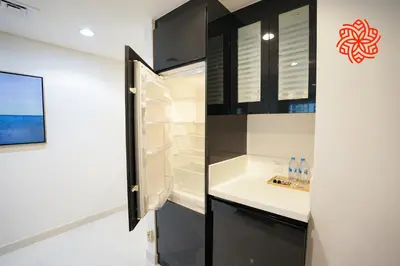 a kitchen with black cabinets and a refrigerator at Alashrafia Saray- Upscale 1bdr apartment in Canal Views in Dubai