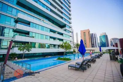 a pool in front of a building with benches and umbrellas at Alashrafia Saray- Peaceful studio in Canal Views in Dubai