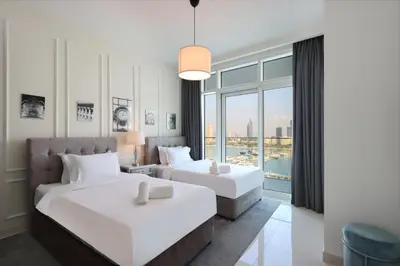 two beds in a room with a large window at 2BR Beachfront Living, Stunning Marina Views in Dubai
