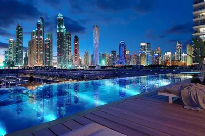 a city skyline at night with a swimming pool at 2BR Beachfront Living, Stunning Marina Views in Dubai