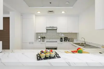 a white kitchen with cupcakes on a table at DAYF-ALI City's Heart Chic 1 BR Huge Terrace and Great Access in Dubai