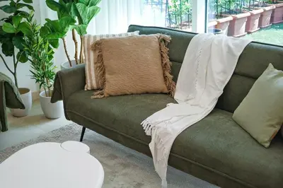 a green couch with a blanket on it in a living room at DAYF-ALI City's Heart Chic 1 BR Huge Terrace and Great Access in Dubai