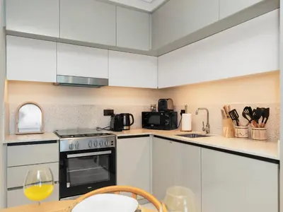 a kitchen with white cabinets and a table with a wine glass at Cozy One Bedroom on the Beach in Dubai Harbour - Prestige Retreats in Dubai