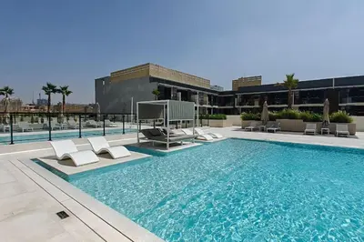 a swimming pool with lounge chairs on top of a building at Vogue JVC Binghatti Corner near Circle Mall, One Bedroom Apartment with Balcony and City View, Access to all Amenities in Dubai