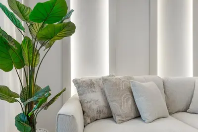 a white couch with pillows and a plant at Elegant Retreat with Stunning Burj Khalifa Views in Dubai