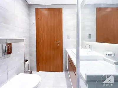 a bathroom with a toilet and a wooden door at Modern 1B with Balcony, Gym & Pool Access in Dubai