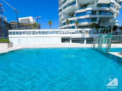 a large swimming pool in front of a building at Modern 1B with Balcony, Gym & Pool Access in Dubai