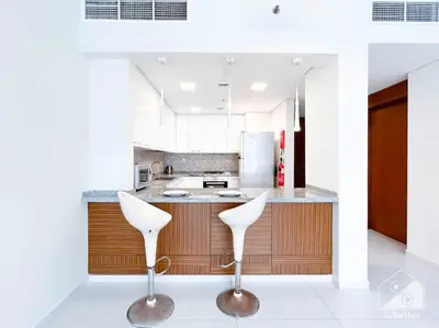 a kitchen with two white chairs and a counter at Modern 1B with Balcony, Gym & Pool Access in Dubai