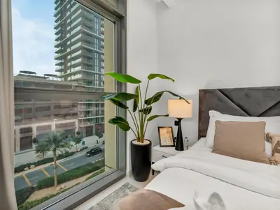 a bedroom with a large window with a plant at Designer Large 1 BR with Private Beach Infinity pool in Dubai Harbour in Dubai