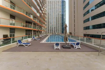a pool on the roof of a building with chairs and an umbrella at Business Bay Gem , Burj Khalifa View in Dubai