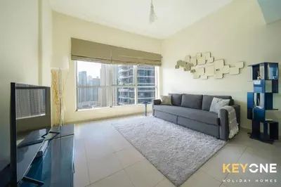 a living room with a couch and a television at Contemporary One Bedroom with Full Marina View in Dubai