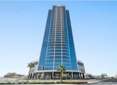 a tall blue building with palm trees in front of it at Charming 1BR in Orchid Residence, Al Barsha South by Deluxe Holiday Homes in Dubai