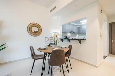 a kitchen and dining room with a wooden table and chairs at Charming 1BR in Orchid Residence, Al Barsha South by Deluxe Holiday Homes in Dubai