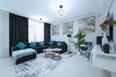 a living room with a black couch and blue pillows at Luxurious 3BDR Serenity Awaits in Damac Hills 2 in Dubai