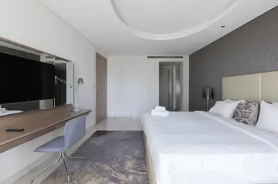 a bedroom with a large white bed and a desk at Cozy 1BR with balcony great view, Damac Towers in Dubai