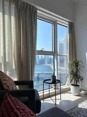 a living room with a large window with a view at Urban Cozy 1BR apartment with Canal view - Free parking in Dubai