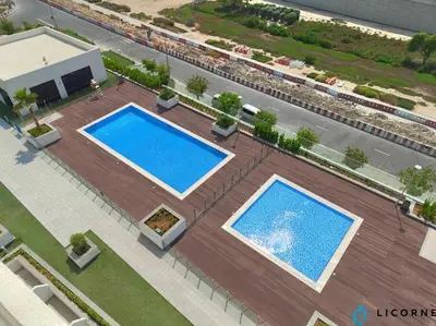 an overhead view of two swimming pools in a courtyard at Modern Contemporary Studio in Azizi Riviera in Dubai