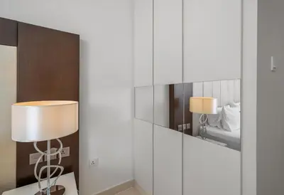 a room with a mirror and a table with a lamp at Luxury 3BR Burj Khalifa View Infinity Pool Spa Gym in Dubai