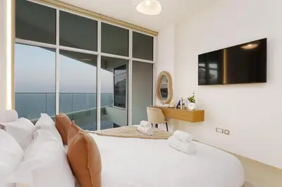 a bedroom with a large white bed and a desk at Dejaview Stays Luxury Apartment with Private Terrace, Burj & Sea View in Dubai