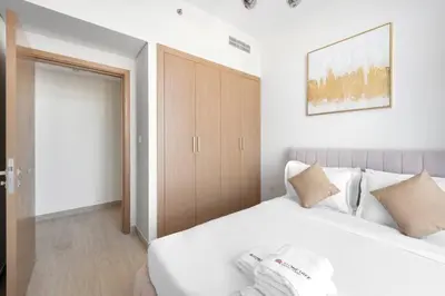 a bedroom with a white bed and a wooden closet at Cozy 2-Bedroom Apartment in Fawad Azizi Residence in Dubai