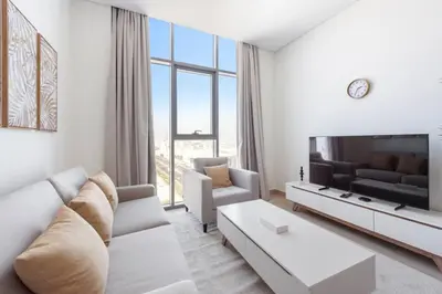 a white living room with a couch and a tv at Cozy 2-Bedroom Apartment in Fawad Azizi Residence in Dubai