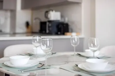 a table with wine glasses and plates on it at Cozy 2-Bedroom Apartment in Fawad Azizi Residence in Dubai