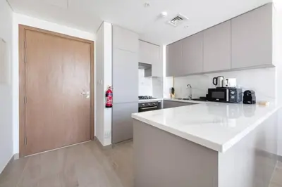 a kitchen with white counters and a wooden door at Cozy 2-Bedroom Apartment in Fawad Azizi Residence in Dubai