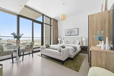 a white bedroom with a bed and a table and chairs at Modern Studio Near To Park in Dubai