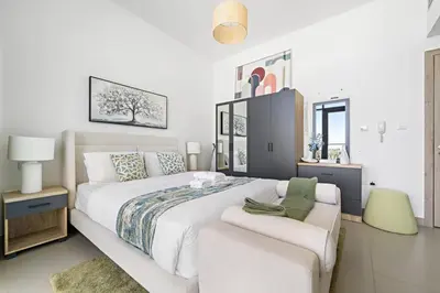 a white bedroom with a large bed and a couch at Modern Studio Near To Park in Dubai