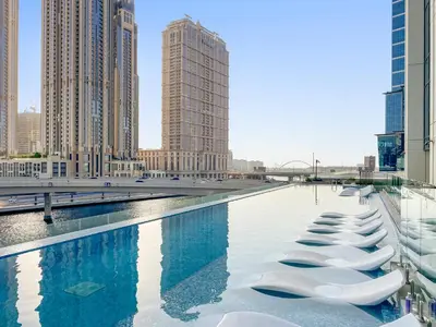 a row of white chairs in a pool in a city at ALiving Elegant 1BR I Near Burj Khalifa & Dubai Mall I Missoni Tower- 607 in Dubai