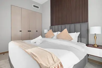 a bedroom with a large white bed with a wooden headboard at ALiving Elegant 1BR I Near Burj Khalifa & Dubai Mall I Missoni Tower- 607 in Dubai