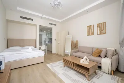 a white bedroom with a bed and a couch at Modern studio near the beach in Dubai