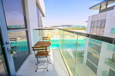 a balcony with two chairs and a swimming pool at Spacious 1BR Burj Khalifa Views in District One Meydan in Dubai