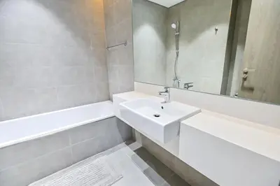 a white bathroom with a sink and a bath tub at 1BR Close to Crystal Lagoon in District One Meydan in Dubai