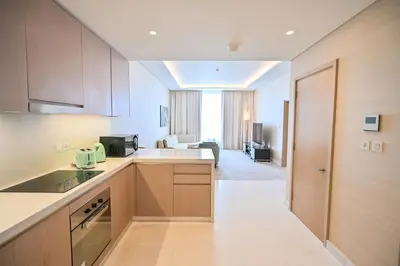 a kitchen with wooden cabinets and a living room at Luxury 1-BR with Stunning Views in Palm Tower by Luxe Shortlet in Dubai