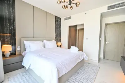 a bedroom with a large white bed with a chandelier at Amazing 1 Bedroom in District One Meydan in Dubai