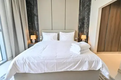 a bedroom with a white bed with white sheets and pillows at Amazing 1 Bedroom in District One Meydan in Dubai