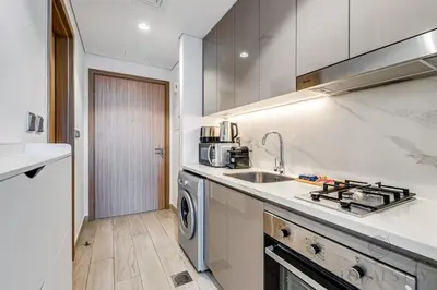 a white kitchen with a sink and a dishwasher at GLOBALSTAY Azizi Riviera 45 in Dubai