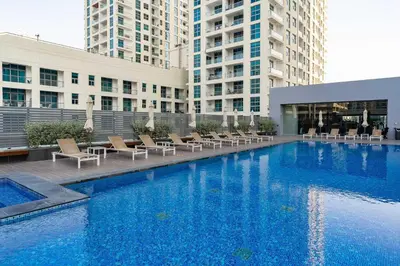a large swimming pool with chairs and buildings at Beautiful Stylish Apartment with Marina Views in Dubai