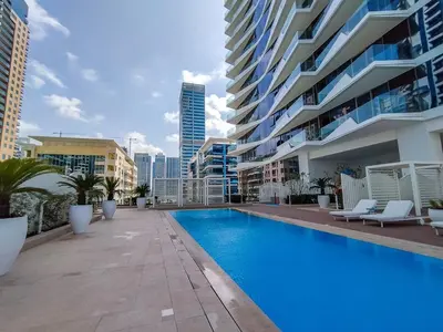 a swimming pool in front of a large building at AirDXB - Exceptional 3bedroom with the incredible view in Dubai Marina in Dubai