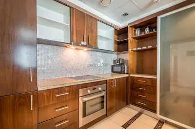 a kitchen with wooden cabinets and stainless steel appliances at Elegant 2BR in Park Island Bonaire, Dubai Marina by Deluxe Holiday Homes in Dubai
