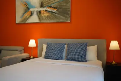 a bedroom with a bed with an orange wall at Cozy studio in Business Bay Dubai in Dubai