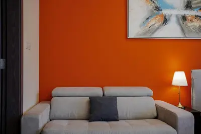 a living room with a couch and an orange wall at Cozy studio in Business Bay Dubai in Dubai